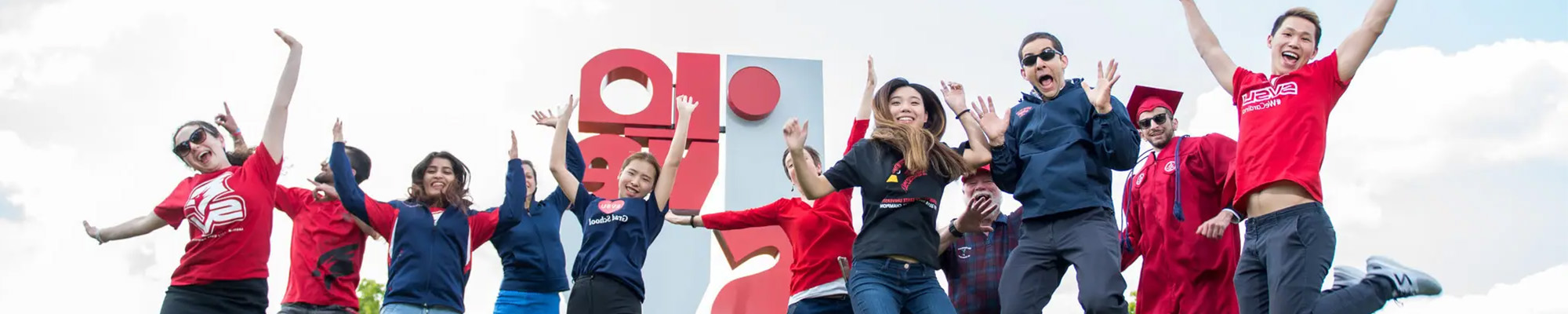 International students jumping into the air in front of I LOVE SVSU artwork
